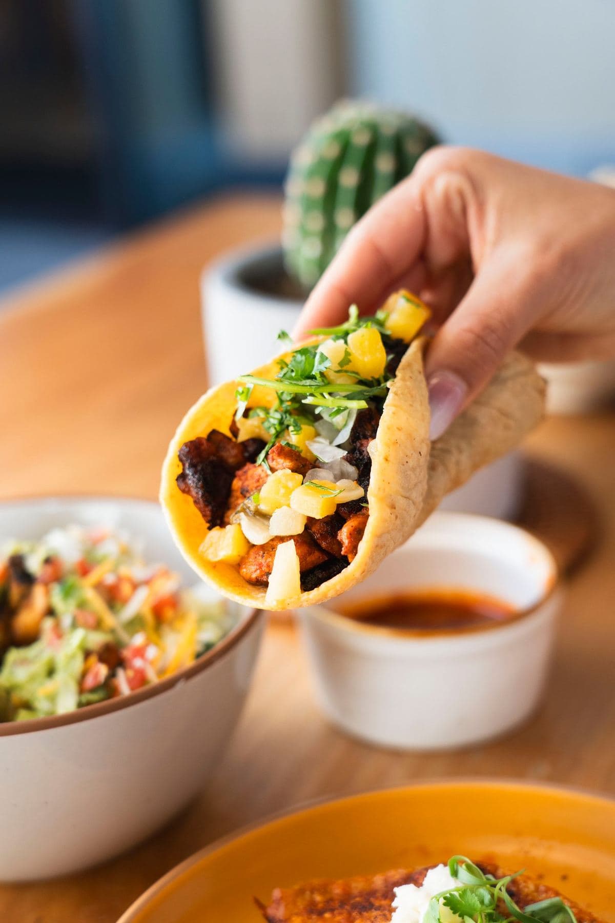 Al pastor taco with fresh pineapple, onion and cilantro on a handmade corn tortilla