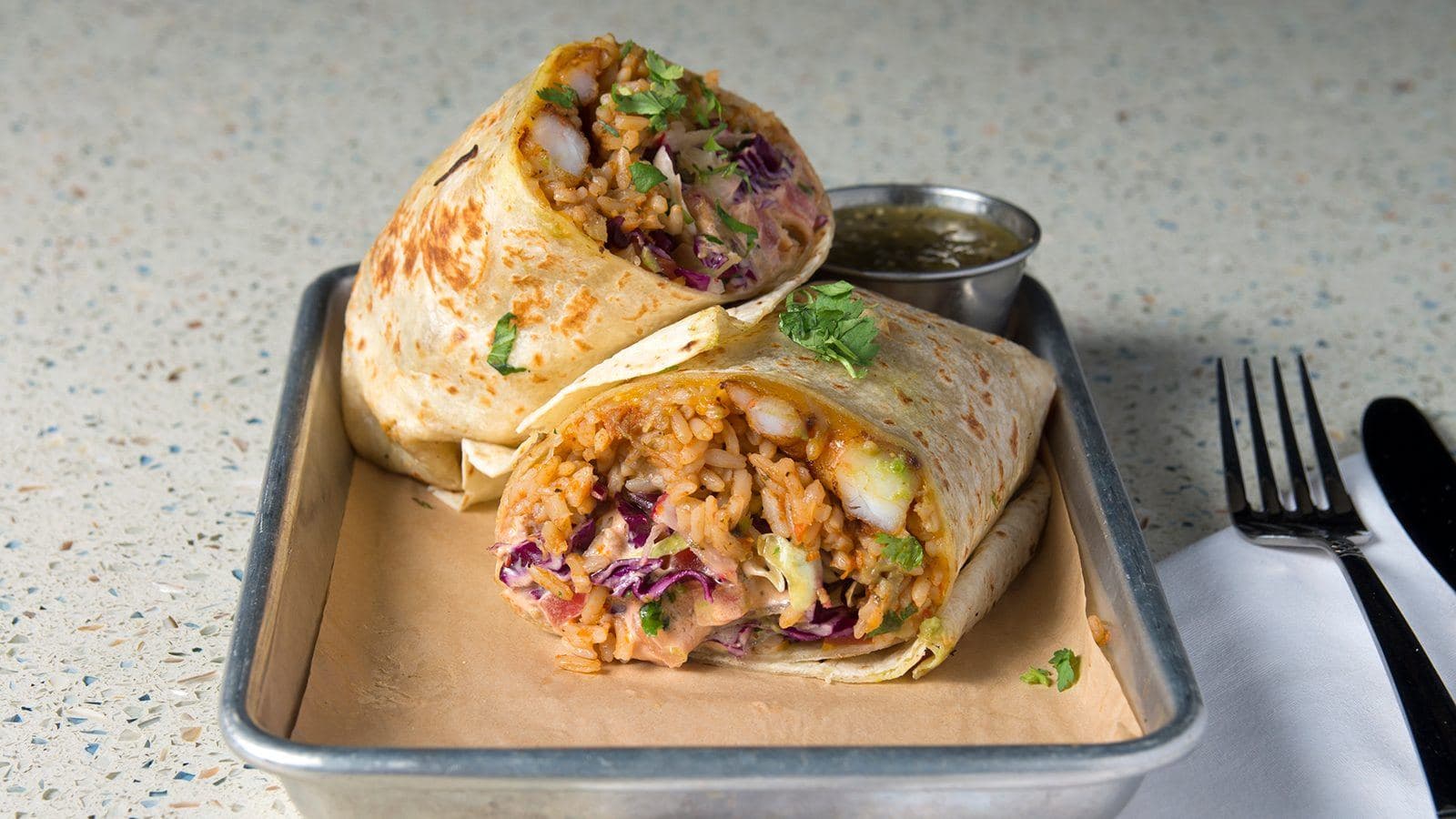 Baja shrimp burrito cut in half with cilantro slaw and chipotle crema