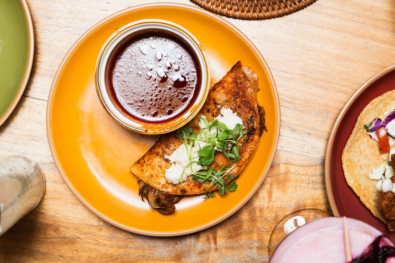 Birria tacos with melted cheese and a cup of consomé for dipping