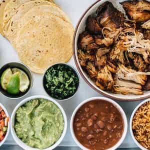 Carnitas family-style taco kit with tortillas and sides