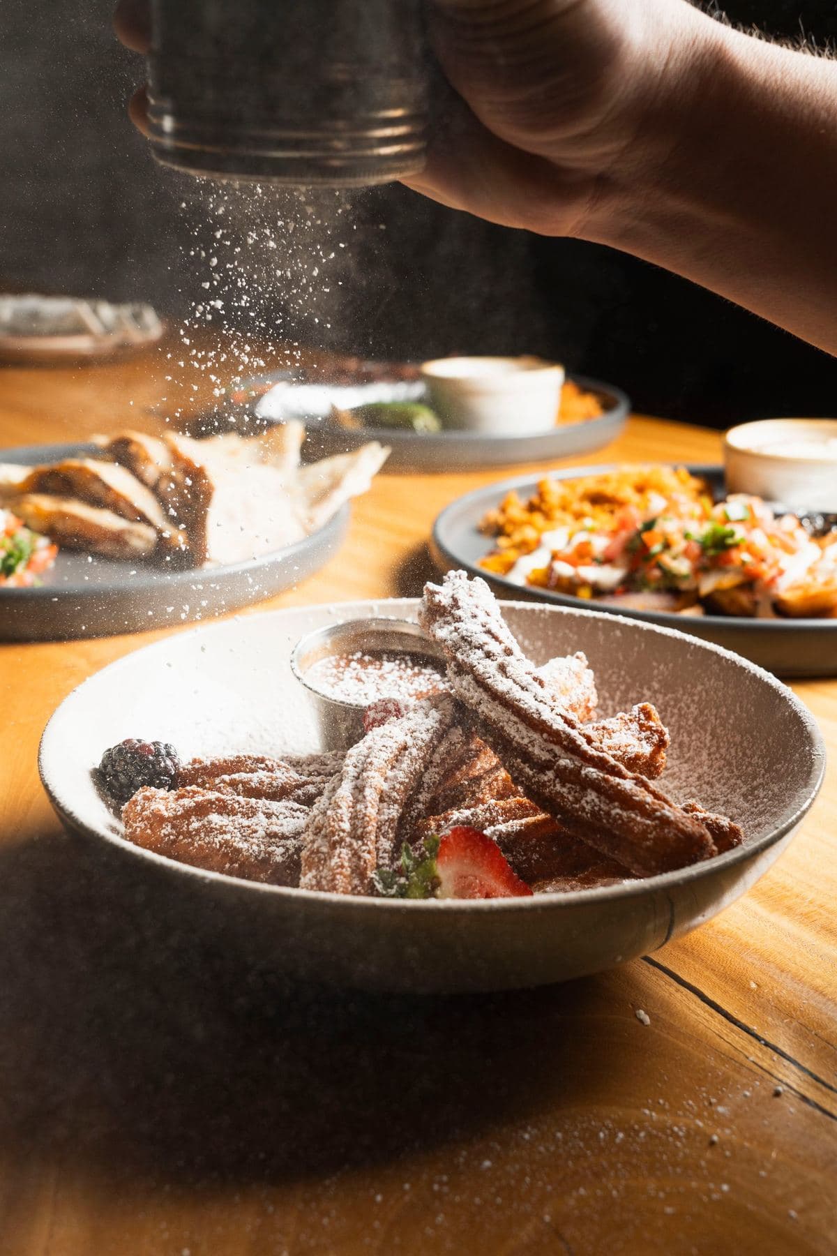 Churros being dusted with cinnamon sugar