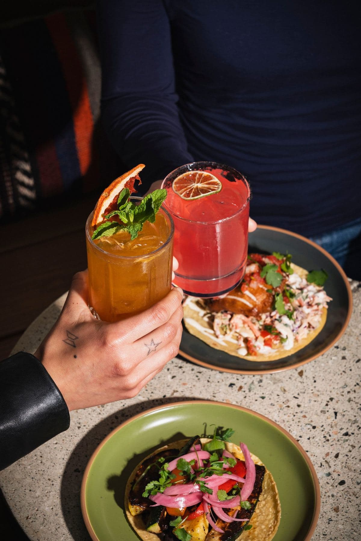 Friends toasting cocktails over a table of tacos