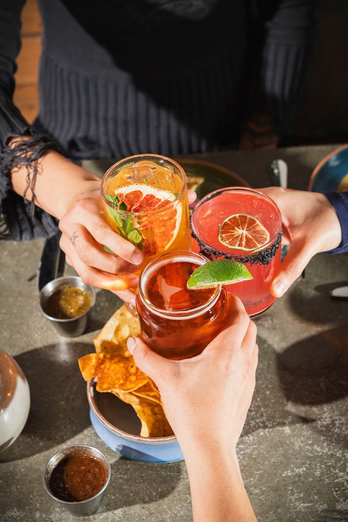 Group toasting with cocktails over chips and salsa