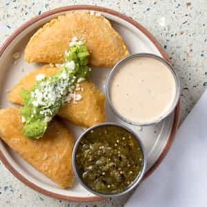 Trio of fried masa empanadas with Oaxaca cheese, guacamole and chipotle crema