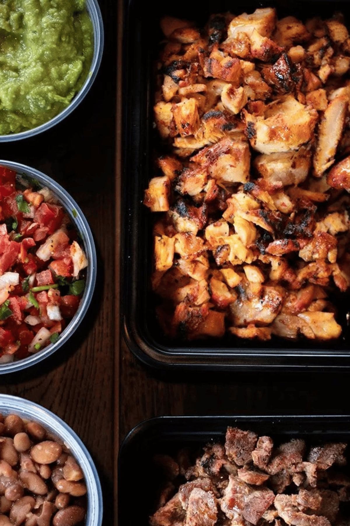 Taco catering trays of pollo asado and carne asada with guacamole, pico and beans