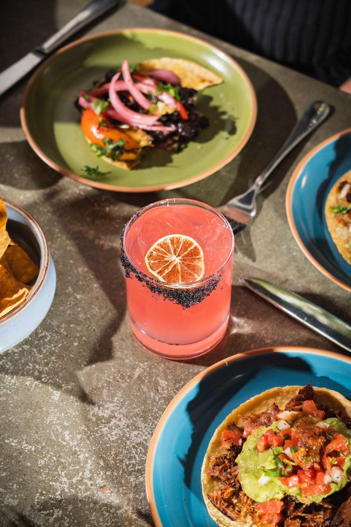 Tacos, salad and a pink margarita shared at the table