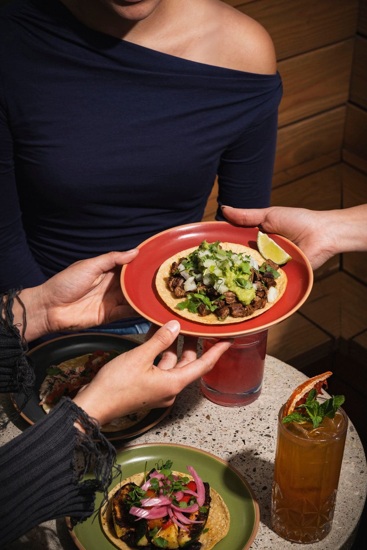 Server handing a plate of tacos across the table