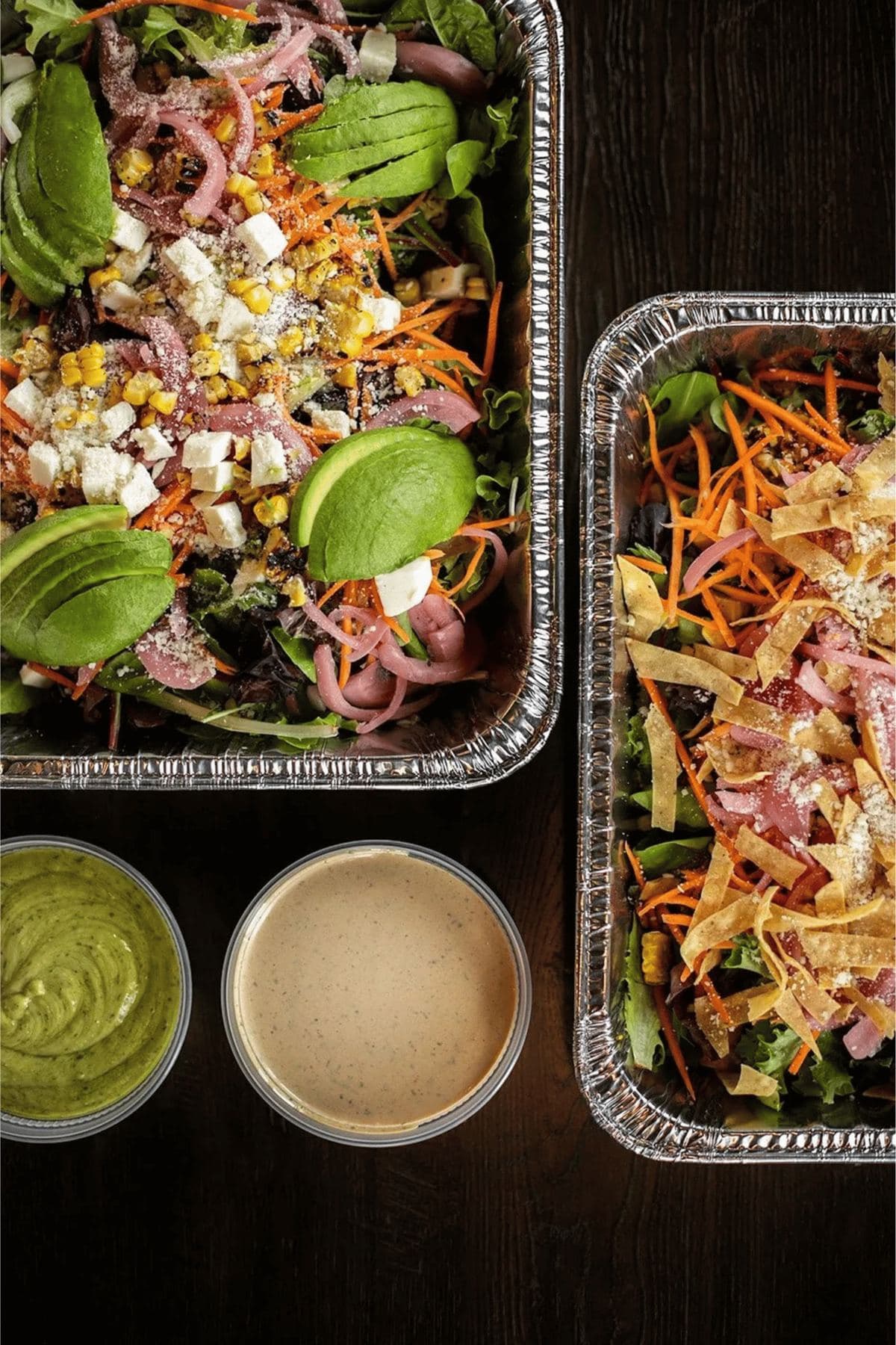 Catering trays of Mexican Cobb and Casero Greens salads with dressings