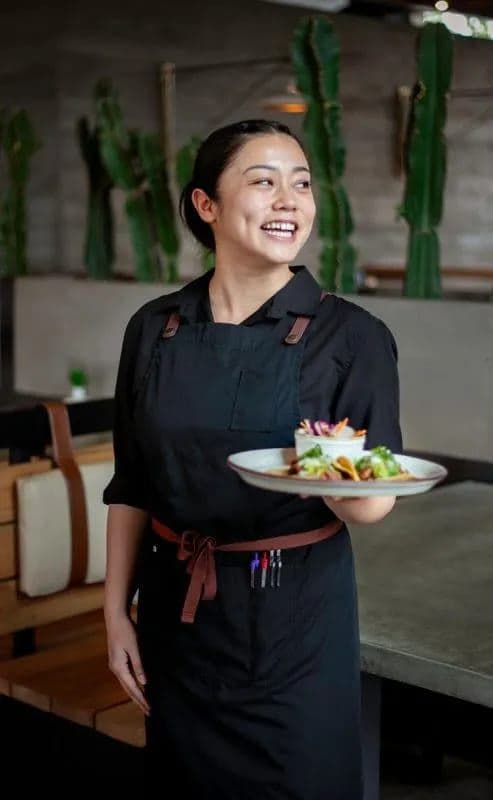 Casero server smiling while carrying a plate